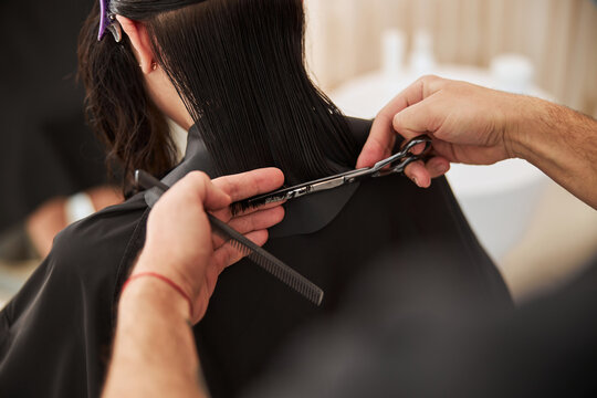 Coiffeur hands using a pair of scissors and a comb