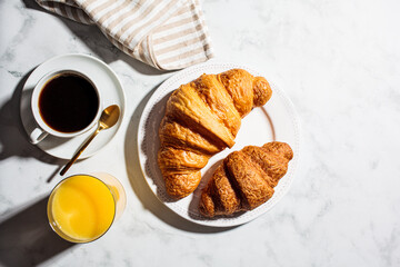 Breakfast background. Fresh croissants, coffee and juice on white marble background.