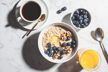 Breakfast concept. Oatmeal with berries and nuts, a cup of coffee and a glass of orange juice on...