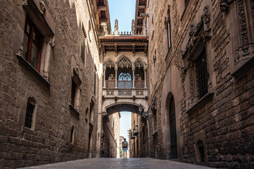 A male traveler with a backpack visiting the Gothic quarter of the city of Barcelona, Spain  - obrazy, fototapety, plakaty