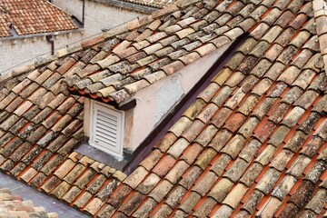 An old tiled roof of a European house with a dormer