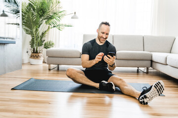 Man on a mat doing some exercise at home using cellphone to help training