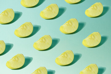 Creative pattern of apple slices on a pastel birch background with trendy sunlight.