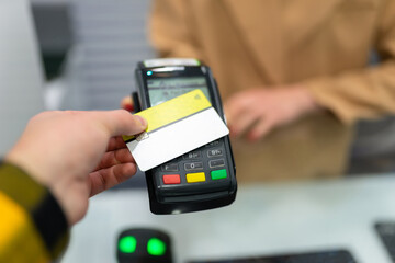 Contactless payment at the terminal. Man pays for the purchase by leaning the card against the pos terminal