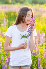 Happy teenage girl smiling outdoor. Beautiful young teen woman resting on summer field with blooming wild flowers green background. Free happy kid teenager girl childhood concept