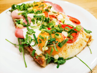 Two fried eggs cooked with tomato sauce and vegetables served with two pieces of homemade bread in white plate for an healthy breakfast