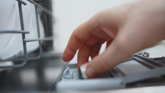 Man putting detergent tablet into dishwasher.