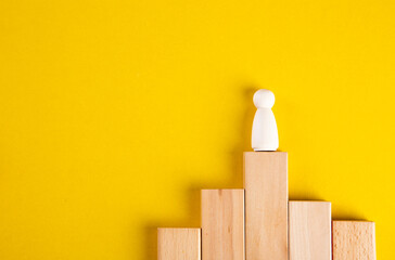 Concept of supremacy leader. Wooden figures on yellow background