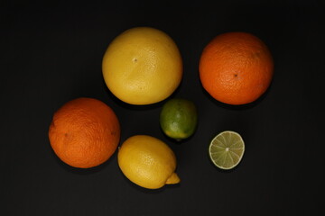 Grapefruit, orange, lemon and lime isolated on a black background. Citrus fruits in the section. Citrus slices. Still life of fruit.