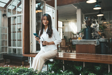 Cute asian young woman sitting in cafe with coffee and phone