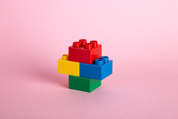 Color plastic building blocks on pink background