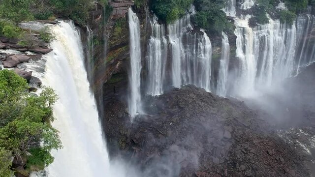 Water rushing down to Calandula waterfalls in Angola looking down on the waterfalls the water hitting the black rocks and the mist all around the waterfall Aerial.