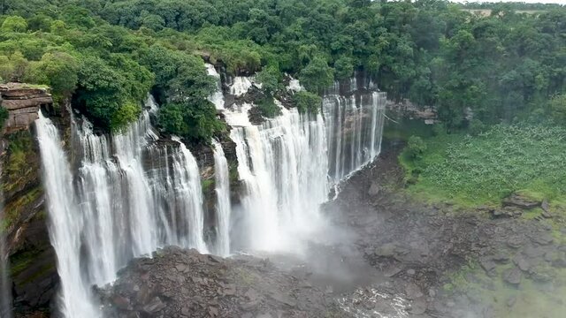 Panning down to Calandula waterfalls in Angola looking down on the waterfalls the water hitting the black rocks and the mist all around the waterfall Aerial