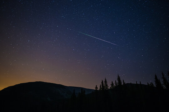 One Meteor (shooting Star) From The Perseids Meteor Shower On A Summer Night With A Clear Sky Full Of Stars In The Mountains With Soft Orange Light From The City On The Horizon, Kananaskis, Canada