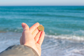 A girl throws a coin into the sea