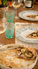 Festive lunch with homemade vegetarian quiche with zucchini, Swiss chard and cheese, white wine. Turquoise water glasses. 