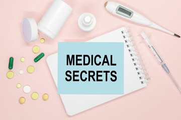 Notebook page with text Medical Secrets on a table, pills and syringe. Medical concept.