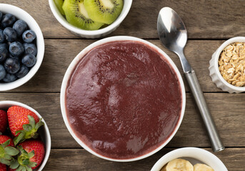 Brazilian typical acai bowl with fruits and muesli over wooden background