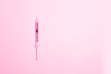 Slim syringe on pink background. Cosmetic injections to restore skin youth.