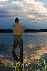 angler catching fish in lake during cloudy day