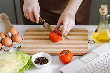 Woman blogger records dietary salad recipe on camera. Online cooking lessons, using laptop in the kitchen.