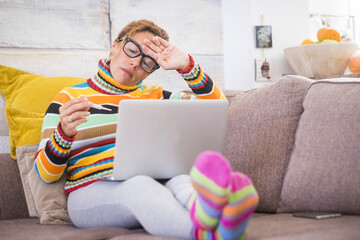 sick and unwell young woman feeling wrong with flu and some virus on the sofa at home. Female with...