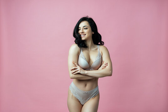 Image of a beautiful woman posing in lingerie on a pink colored background