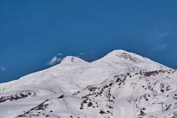Fotobehang View of two peaks of Mount Elbrus, ski slope and pendulum cable car. © IrinaK