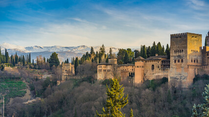 Fototapeta na wymiar View at sunset on the Alcazaba, the medieval fortress part of the Alhambra complex in Granada, Andalusia, Spain, with the Sierra Nevada mountains in the background