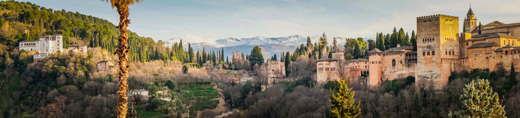 Obraz premium Panorama on the Alhambra complex (Generalife palace and Alcazaba fortifications) and the snow capped Sierra Nevada mountains from the Albaicin district of Granada (Spain)
