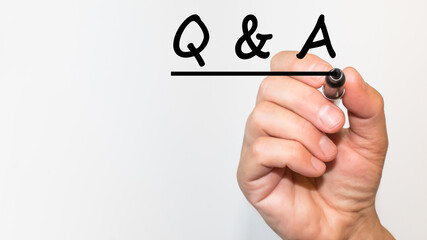 the hand writes text Q AND A with a marker on a white background. business concept