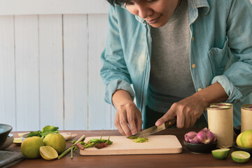 people is slicing fresh chilli he is looking to recipes in the kitchen. reading cooking books of the food menu, salad canned fish how to cook online with social media at home. quarantine concept