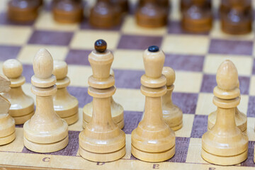 Playing wooden chess on a chessboard. Tactics and strategy. Black and white shapes.