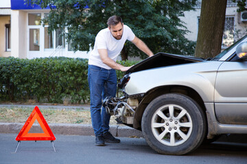 Driver man looking on wrecked car in car accident. Man regrets about fixing car after auto crash....