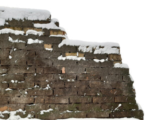 A dilapidated brick wall with uneven masonry covered with snow. There is an empty space on the...