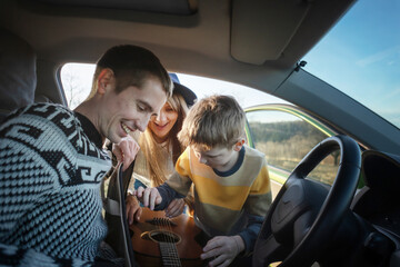Young happy cheerful family with son traveling together by car, road adventure and time together