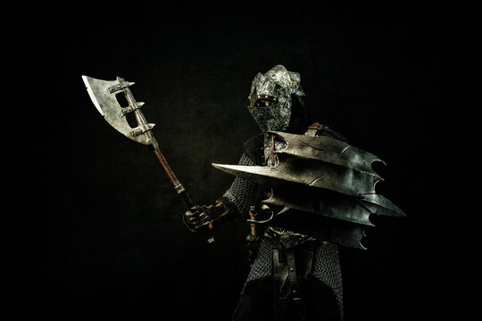 Medieval fighter in armor, in profile, carrying a shield and an ax on his shoulder, in attack position