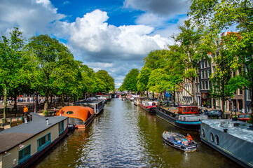 Fototapeta na wymiar Amsterdam, Netherlands - July 7, 2019: Traditional Dutch houseboats in the canals of Amsterdam in the Netherlands on a sunny summer day