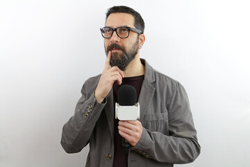 Man with beard wearing casual clothes holding reporter microphone serious face thinking about...