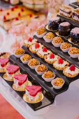 Single serving desserts on a modern stand of a buffet table, wedding candy bar