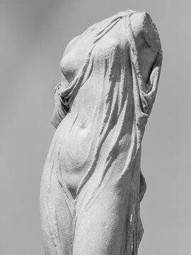 Black and white photo of close-up on headless and armless ancient roman statue showing a sexy female body wearing a transparent tunic