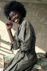 portrait photo of a beautiful dark-skinned girl with afro hair in green dress she sits and...