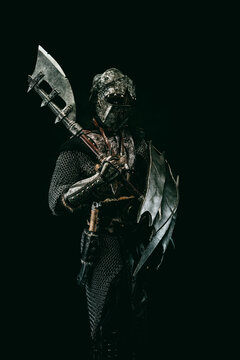 Medieval fighter in armor, carrying a shield and an ax on his shoulder