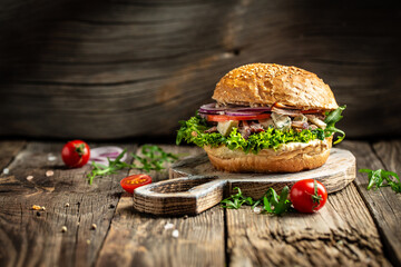 gourmet burger with blue cheese and arugula on rustic wooden background. fast food and junk food...