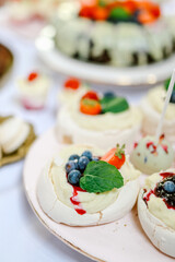 Pavlova dessert decorated with blueberries, cream and  mint on a candy bar close up