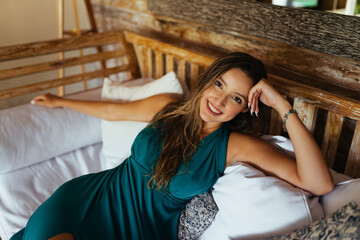 Obraz premium A girl with a luxurious smile relaxes on pillows in a blue dress. High quality photo