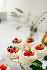 Mini pavlova dessert decorated with blueberries, strawberries cream and  mint on a candy bar close up