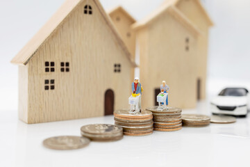 Miniature people: Parent and children with shopping cart standing on coins stack with house and car.  Concept of shopping in housing and vehicles.