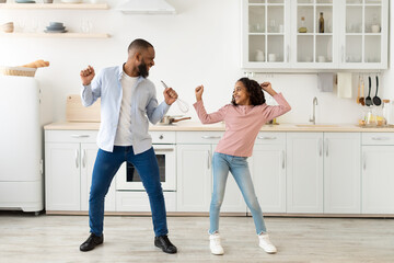 Black dad and daughter dancing while cooking together