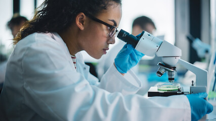 Medical Science Laboratory: Beautiful Black Scientist Looking Under Microscope Does Analysis of...